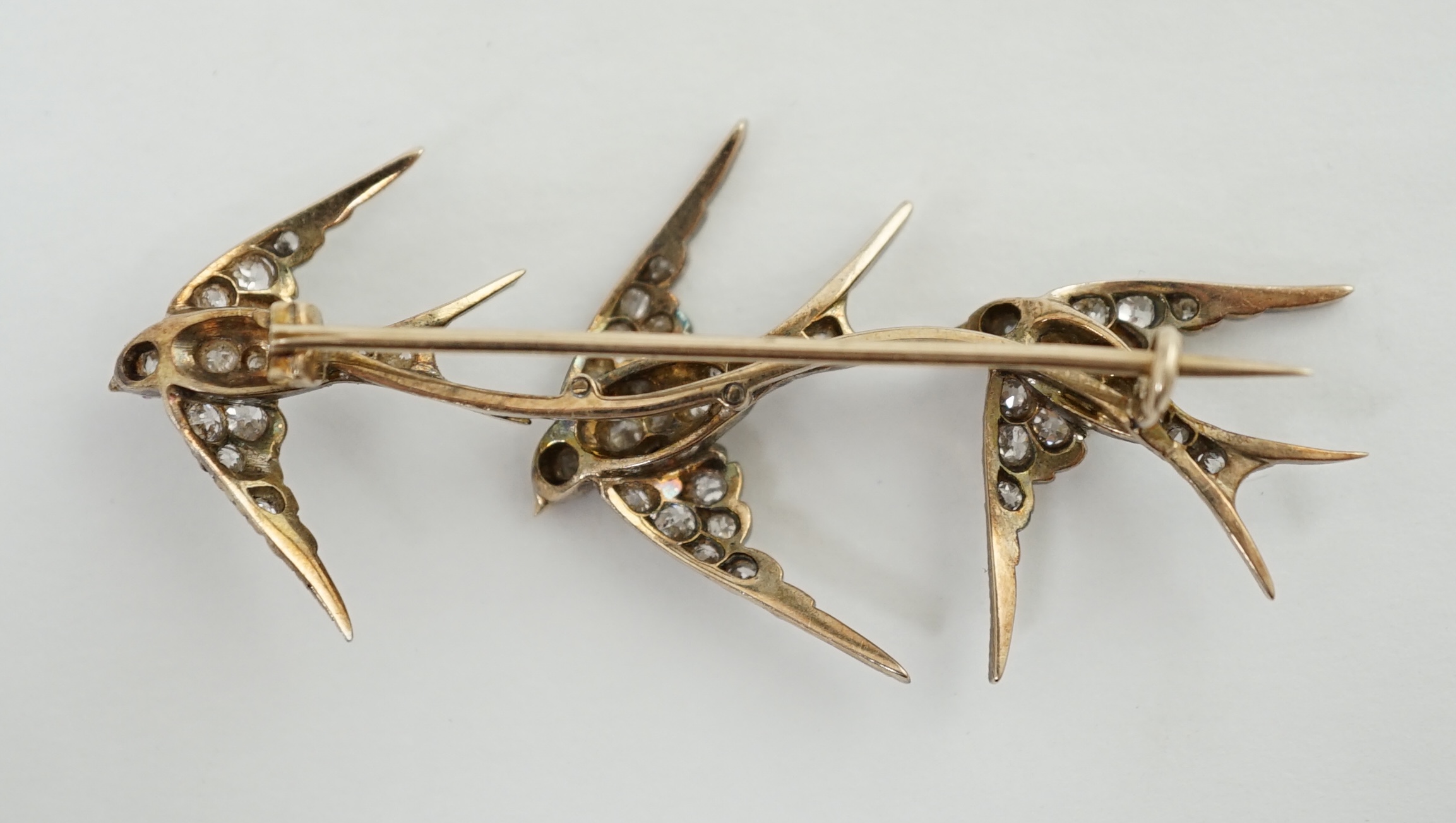 An Edwardian gold and graduated diamond cluster set triple swallow bar brooch